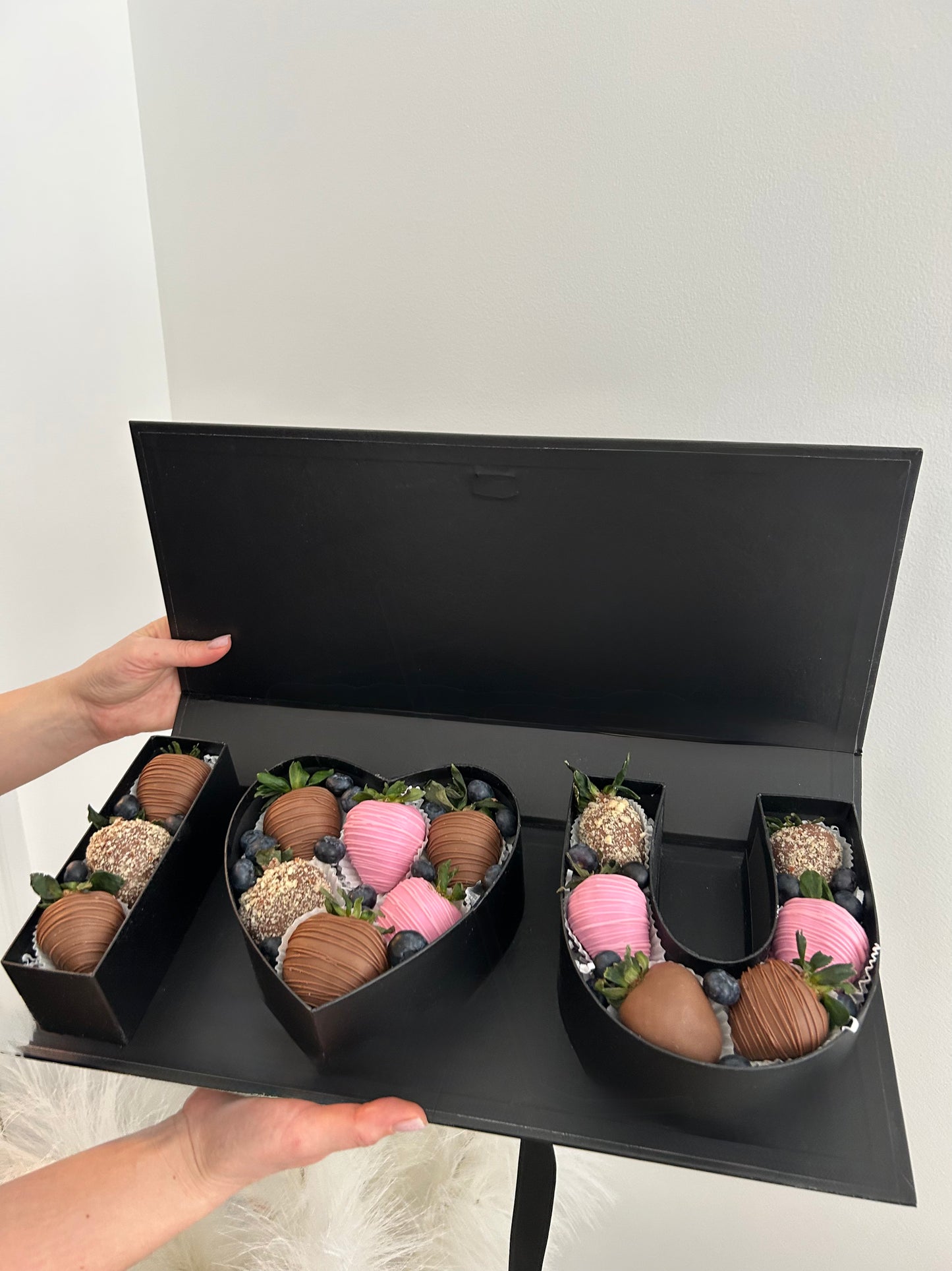 heart-shaped boxes with chocolate-covered strawberries on a white background
