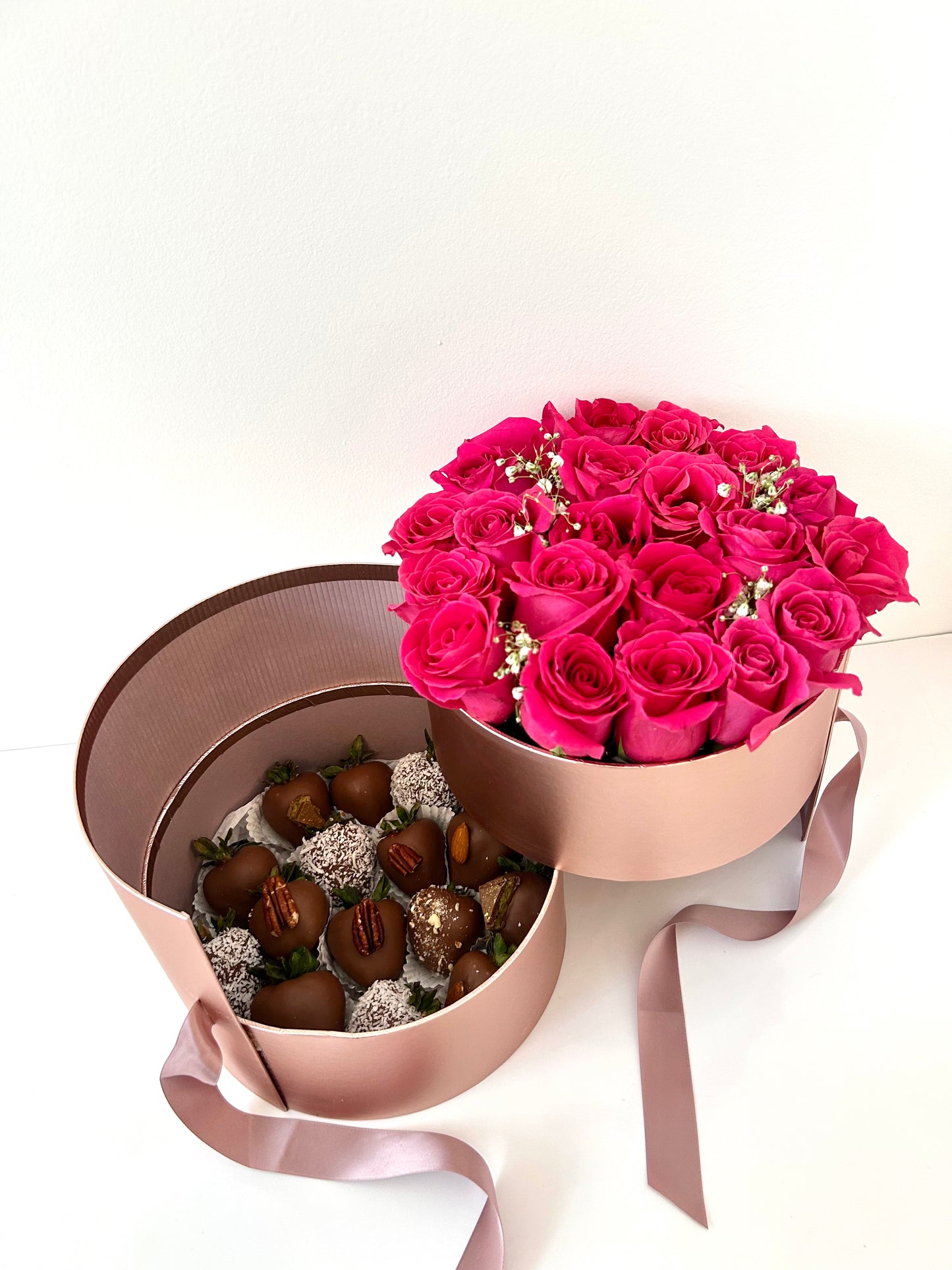 Bouquet of pink roses in a decorative box with chocolate covered strawberries on a white background