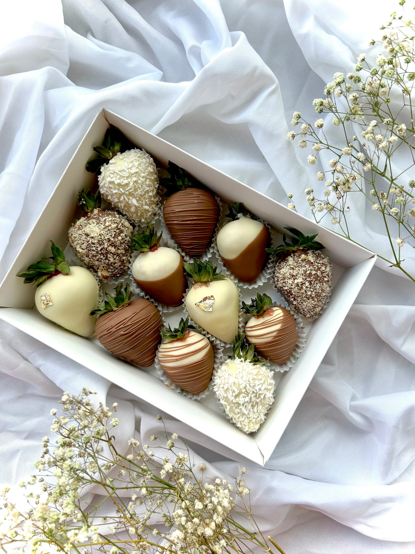 Chocolate covered strawberries in white box on the white background with baby breath flowers.