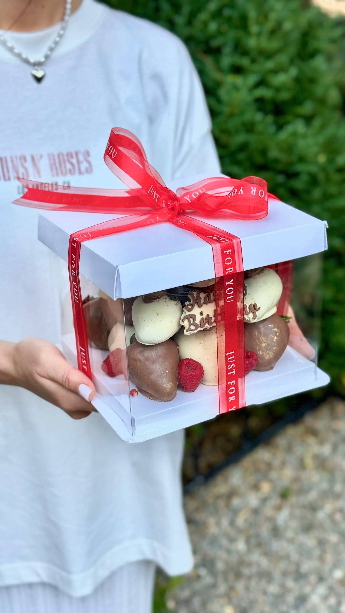 model holds chocolate covered strawberries cube