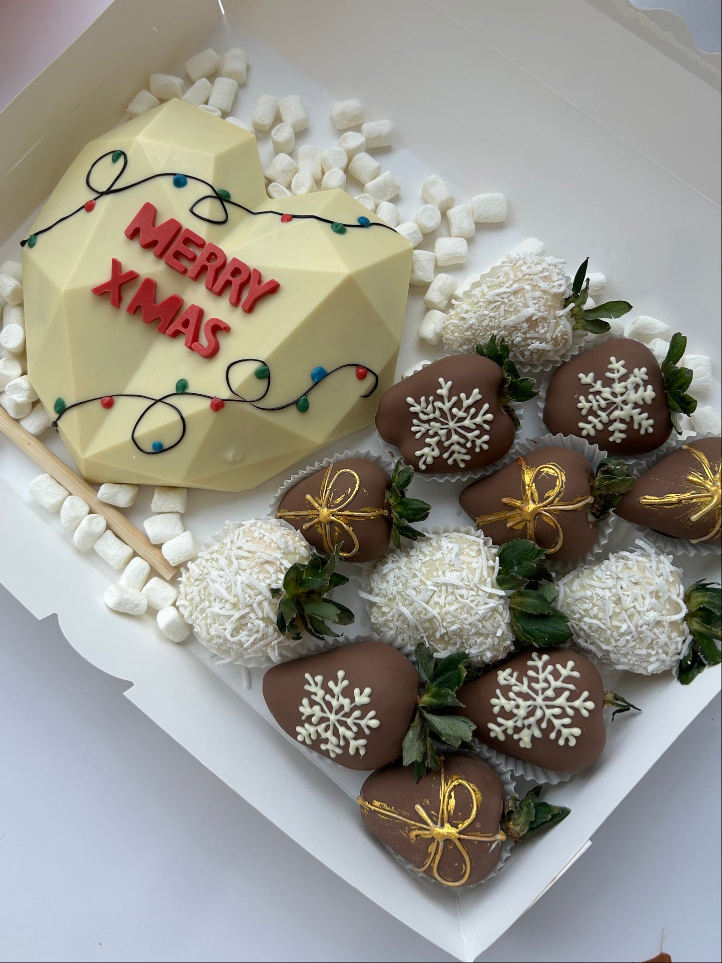 Decorative Christmas cake with chocolate-covered strawberries and a 'Merry Christmas' sign.