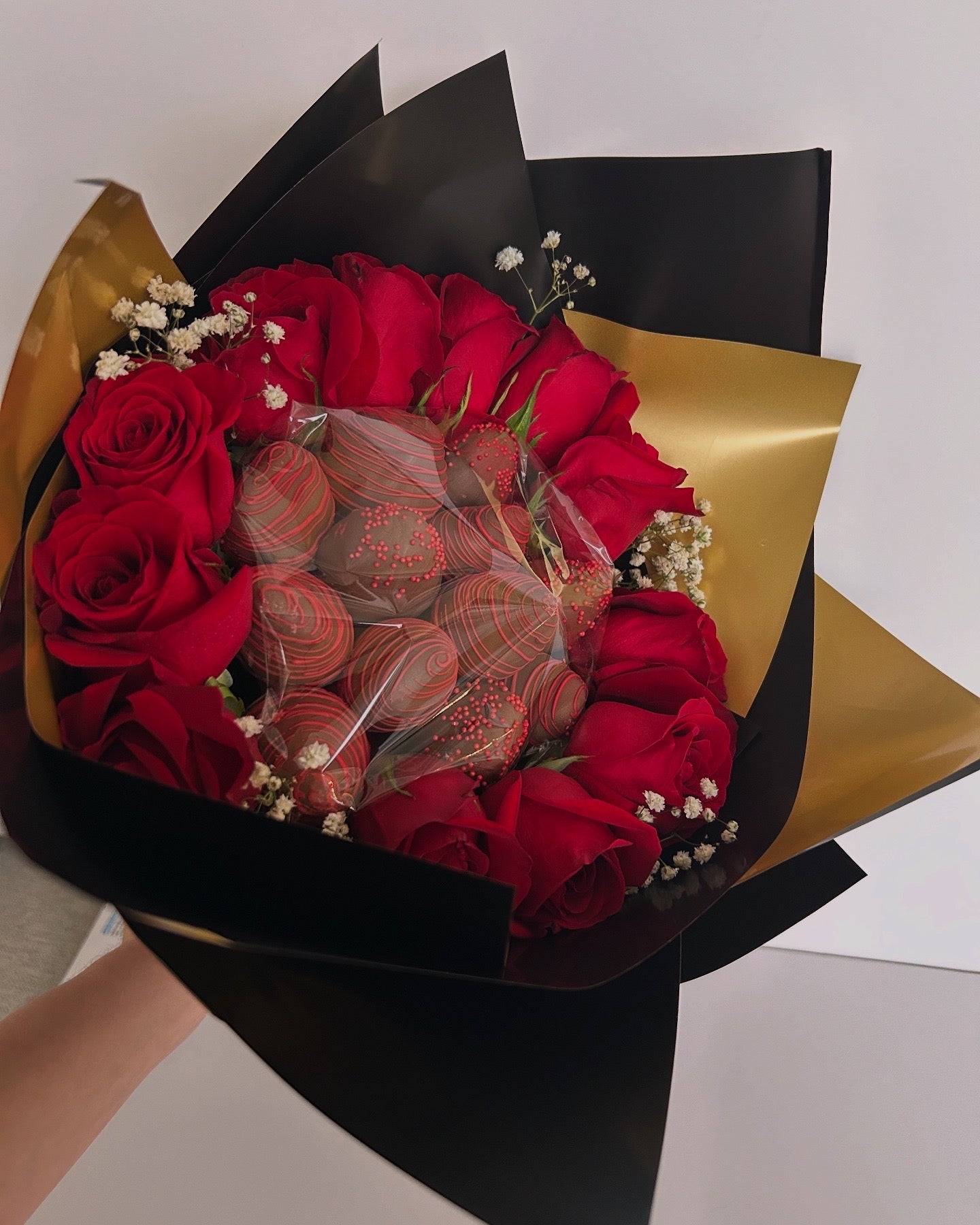 Bouquet of chocolate covered strawberries and roses with black and gold wrapping 