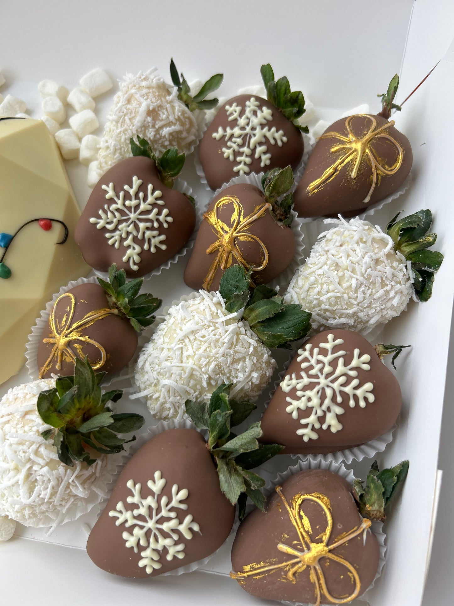 Decorative chocolate-covered strawberries with snowflakes and bows on a white box.