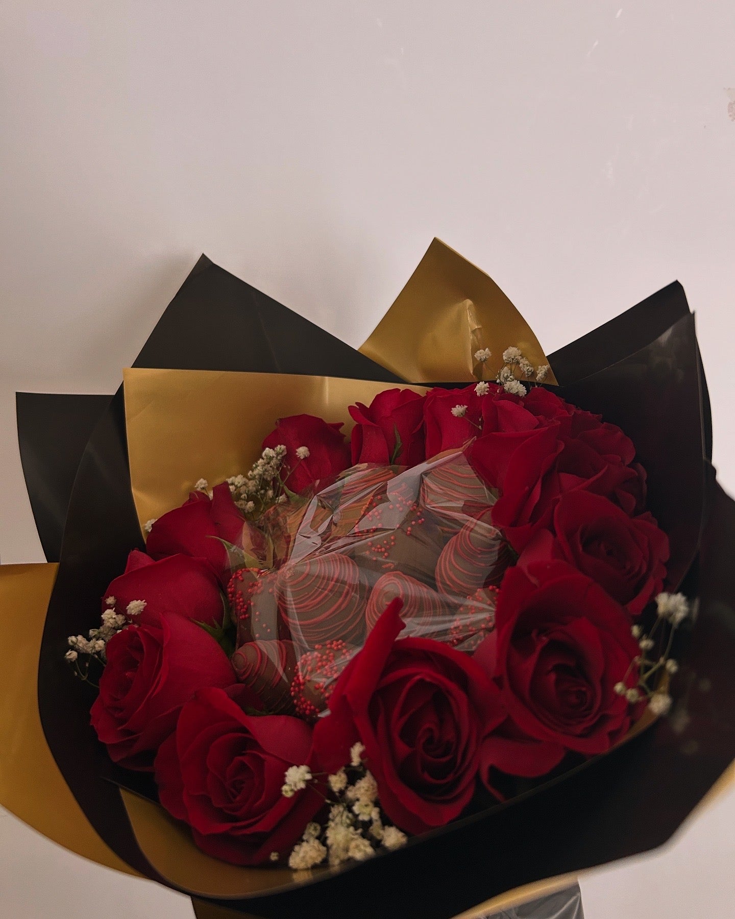 Bouquet of chocolate covered strawberries and roses with black and gold wrapping 