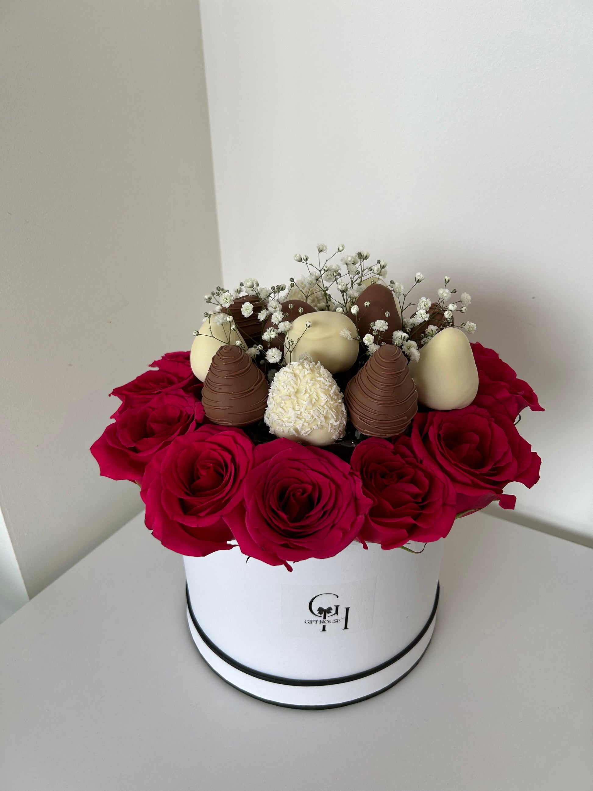 chocolate covered strawberries and red roses in white floral box  on white background
