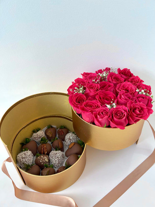 Gold Round-shaped box with pink roses and chocolate covered strawberries on white background