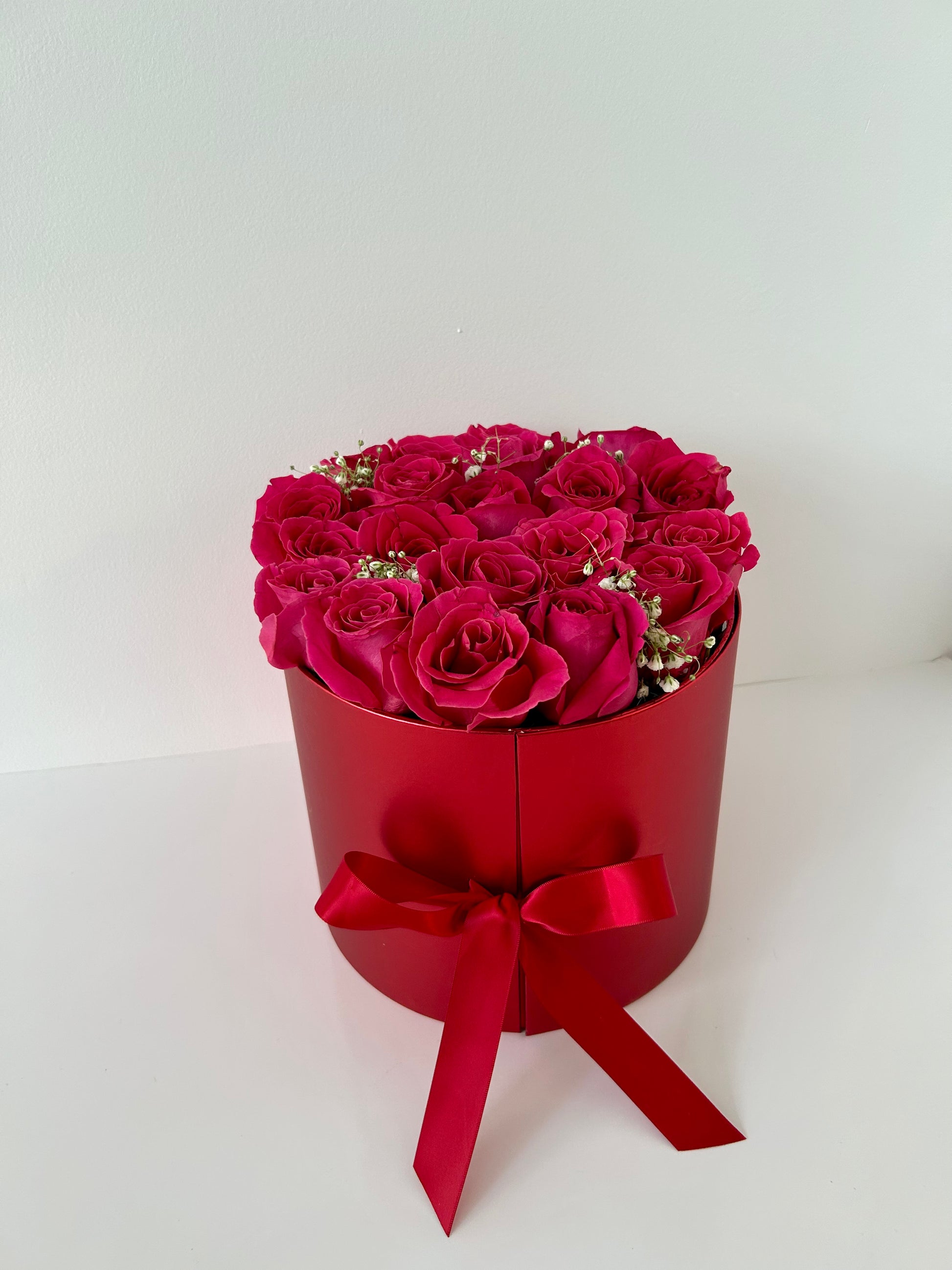 Red box with pink roses and a red bow on a white background