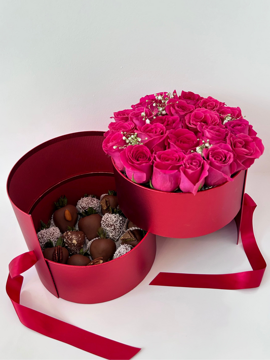 Round-shaped box with pink roses and chocolate covered strawberries on white background