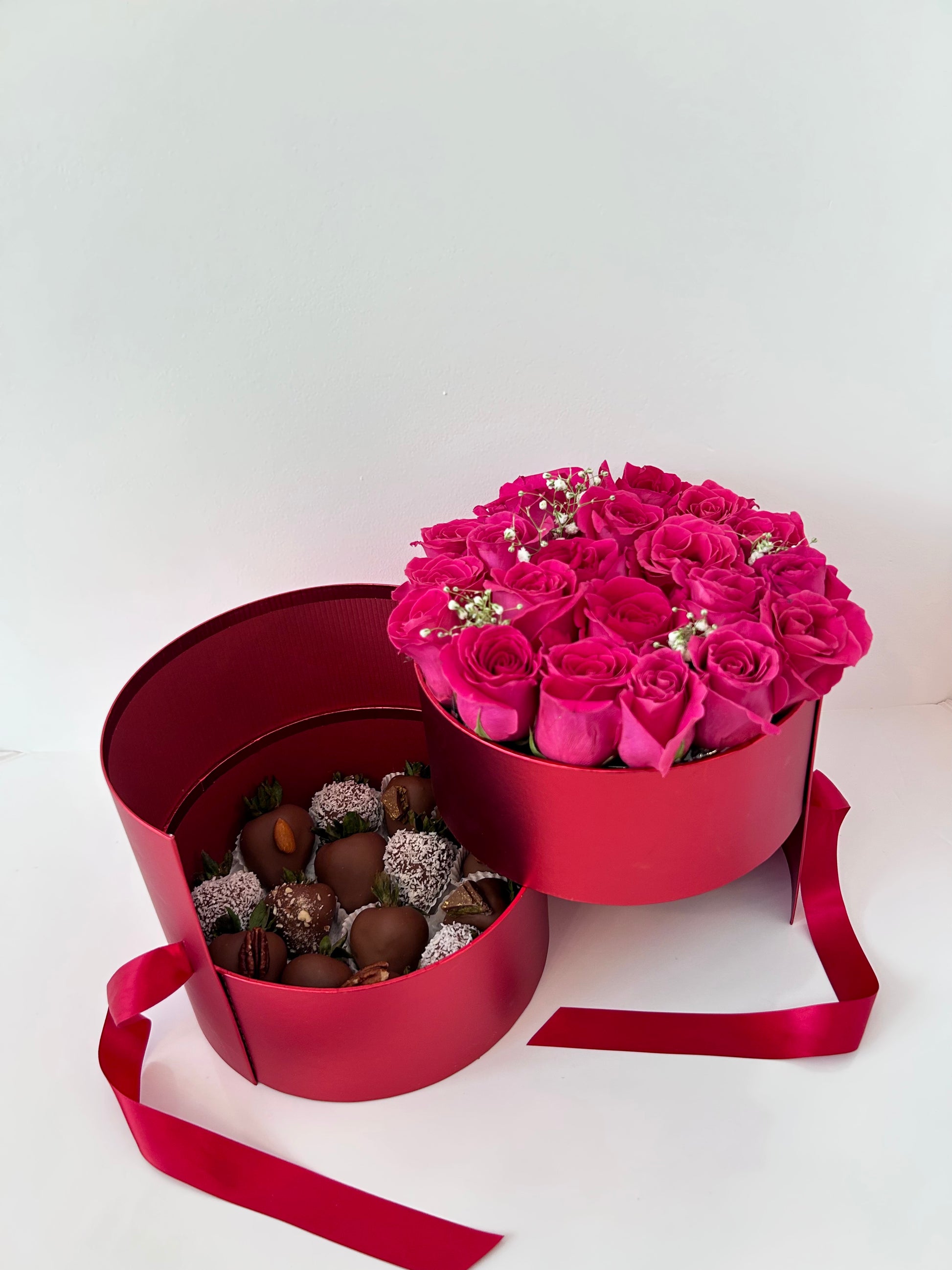 red Round-shaped box with pink roses and chocolates on a white background