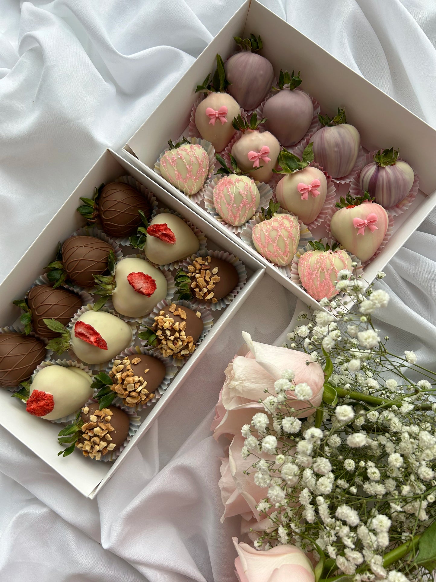 two boxes with chocolate covered strawberries, roses on the background 
