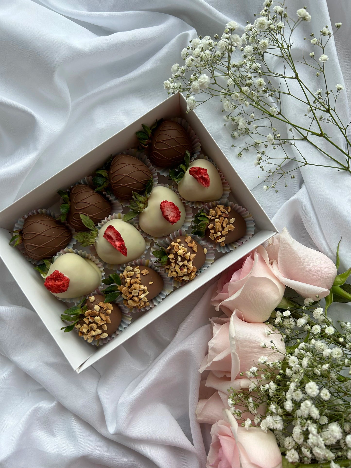 12 chocolate covered strawberries in a white box with roses on background 
