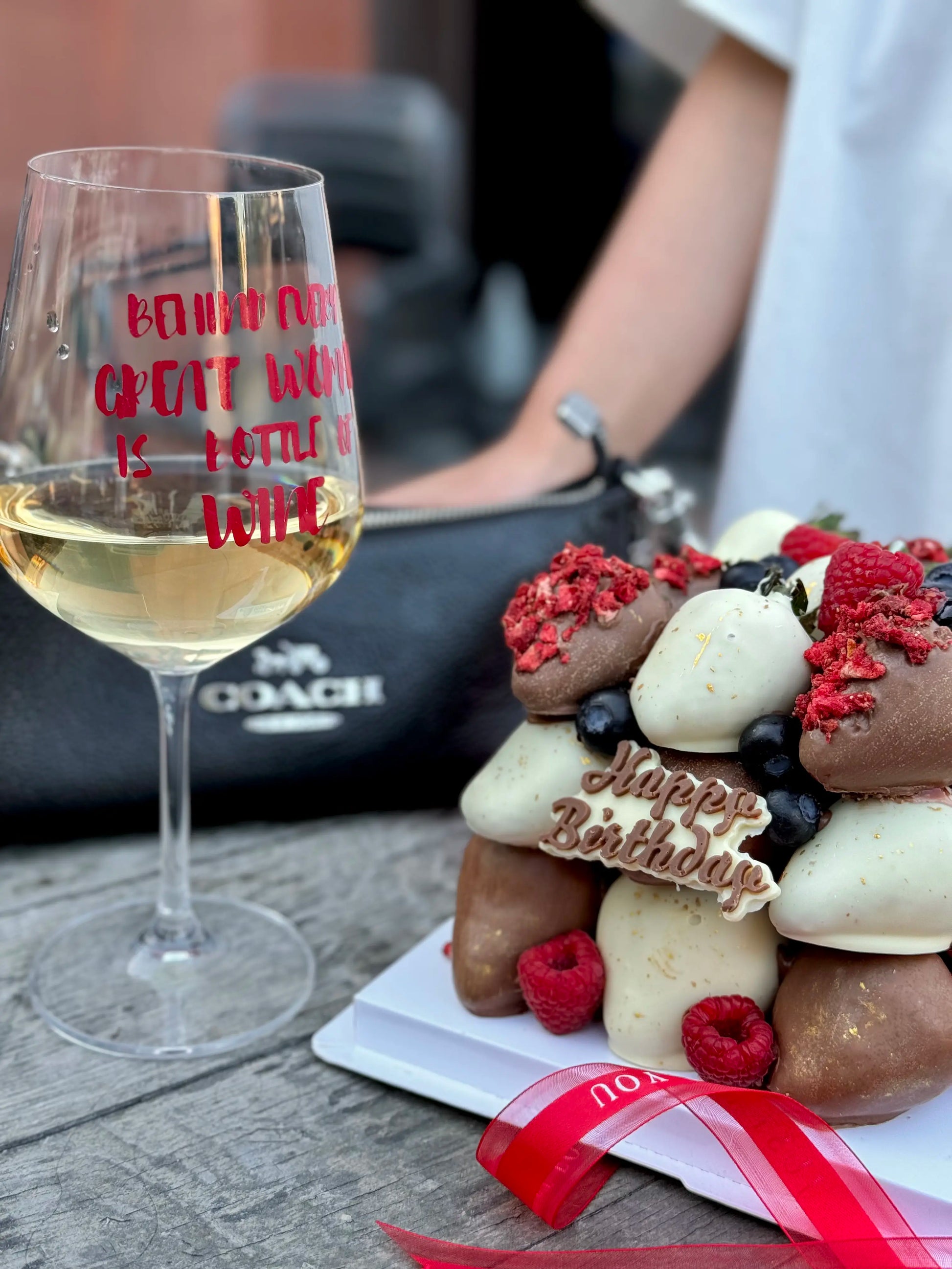 Chocolate dipped strawberry cube with glass of wine and bag on the background 