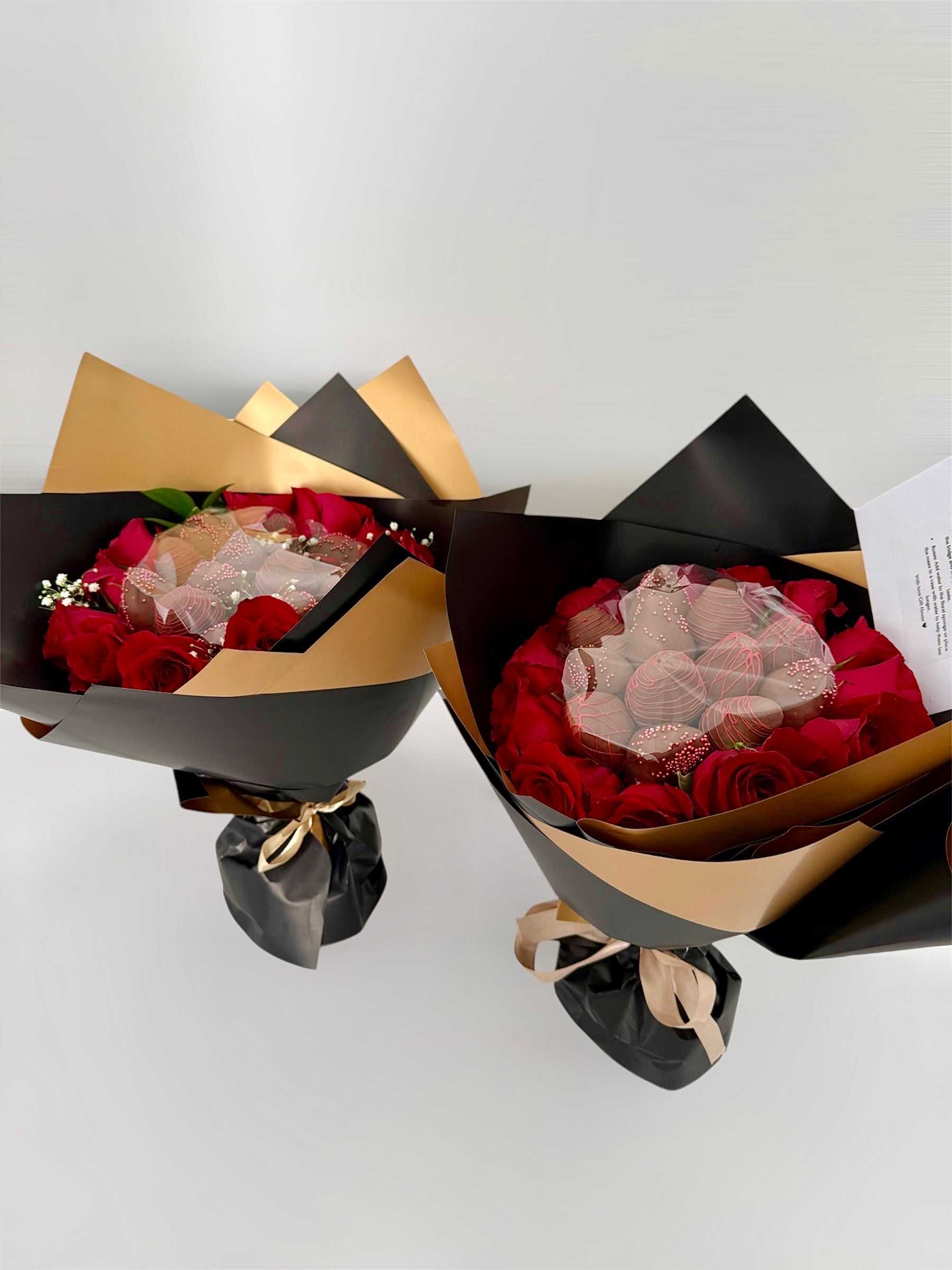 two bouquets with red roses and chocolate dipped strawberries on white background
