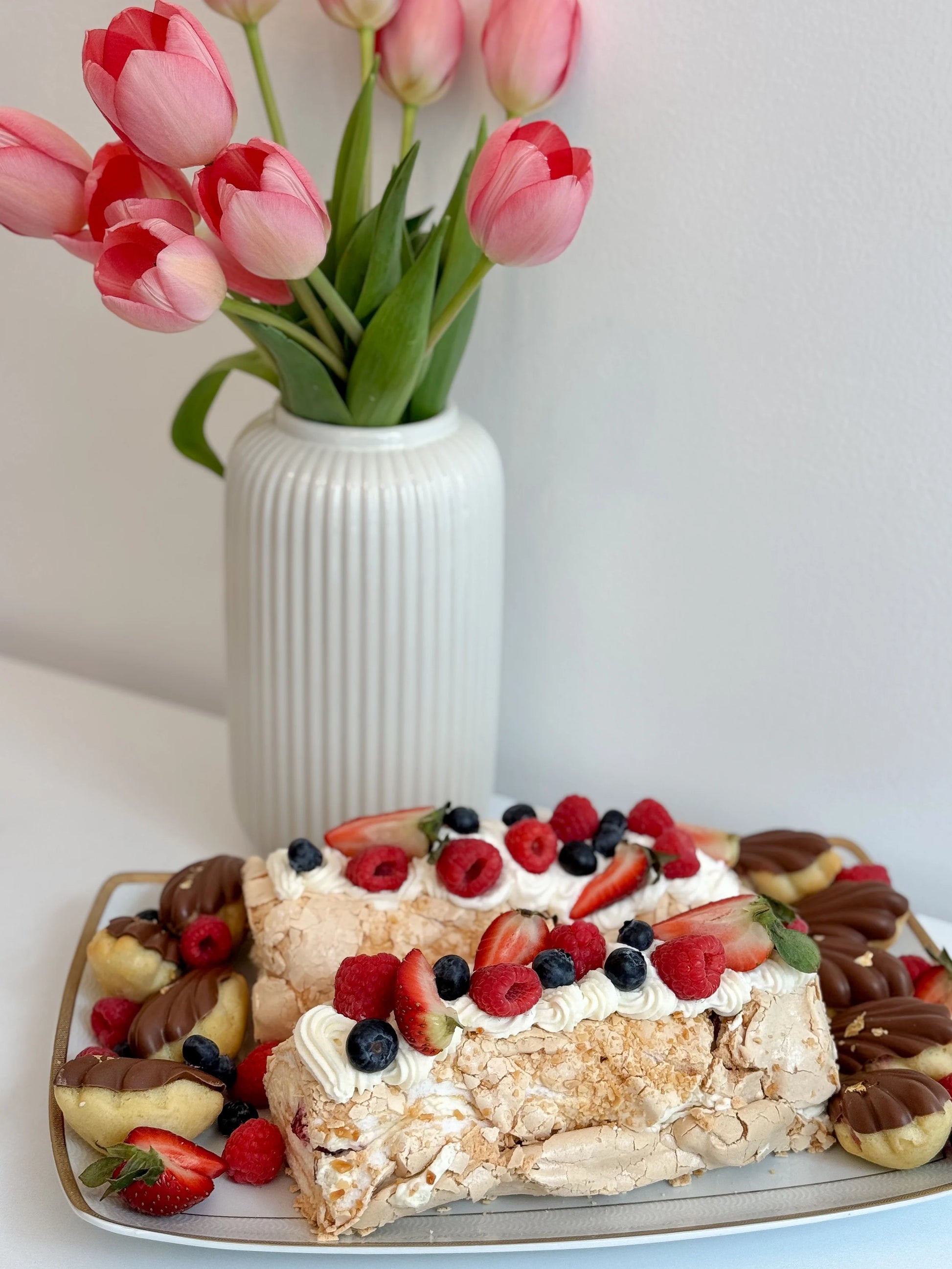 Two-piece meringue roulade set on elegant serving tray with fresh fruit
